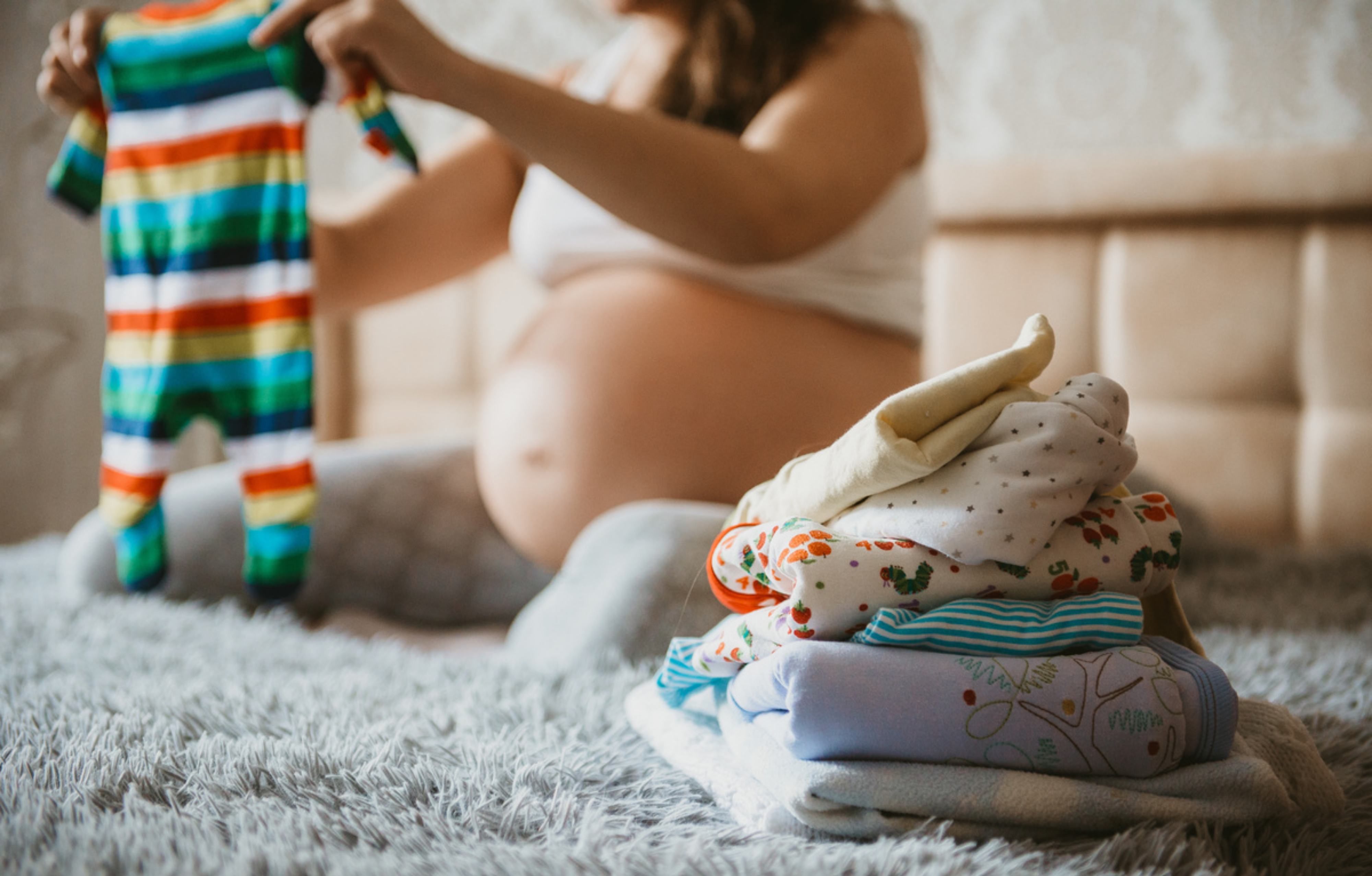 pregnant woman folding clothes on bed